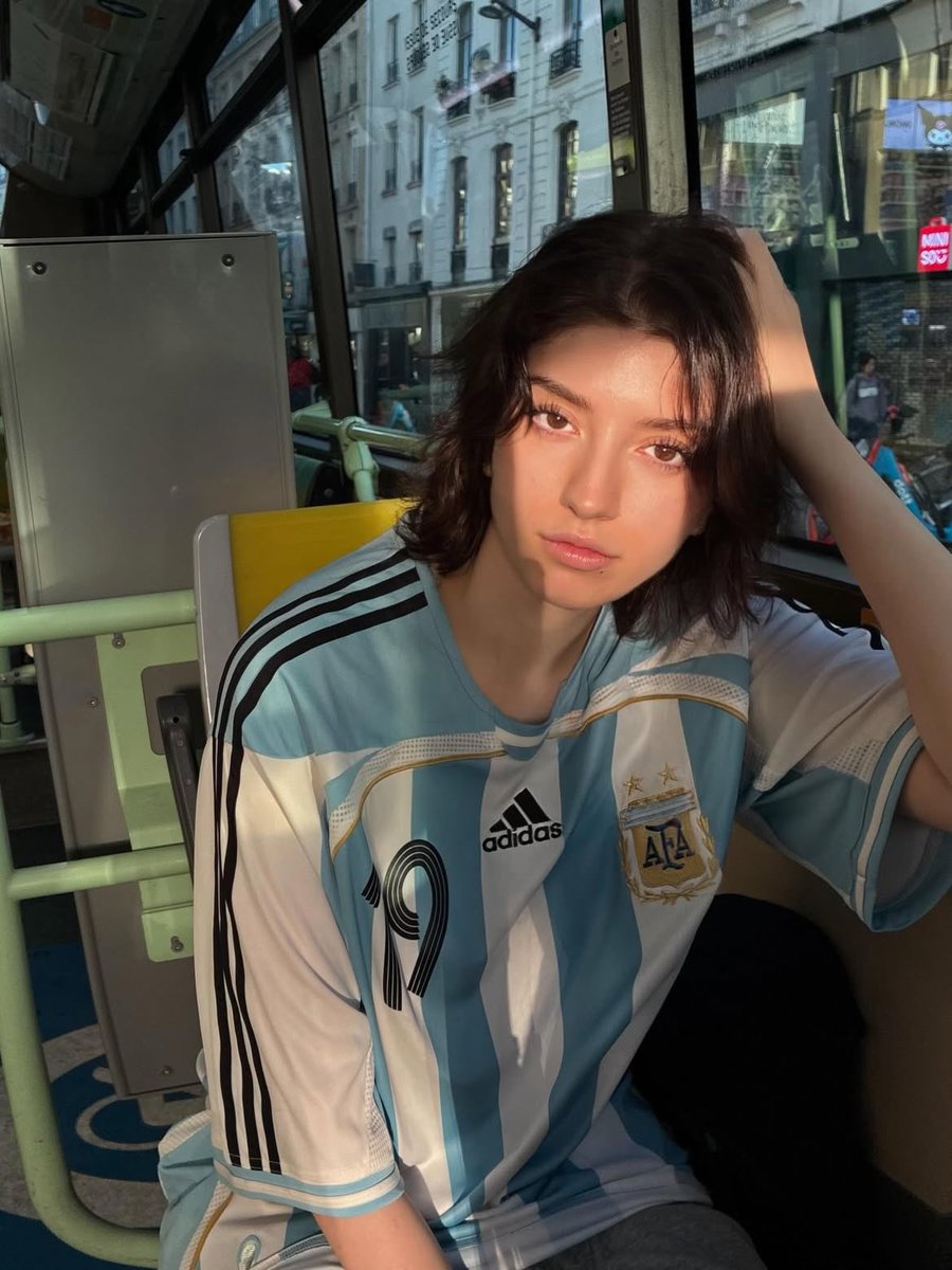 Candid Portrait of a Young Person with Short Wavy Dark Hair Wearing an Oversized Argentina